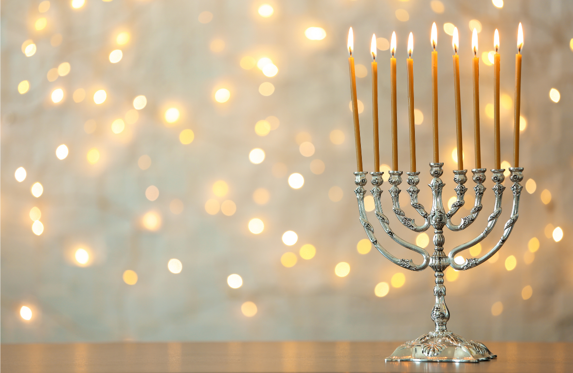Silver Menorah with lit candles against a blurred lights background
